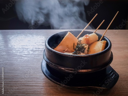 Korean fish cake and vegetable hot soup in black ceramic bowl on wood table photo