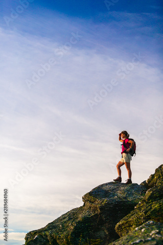 Silhouette of young woman climbing a rock.