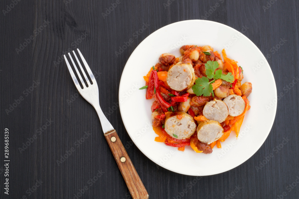 Stewed beans with vegetables and sausages. on black background. Stewed beans with vegetables and sausages. on black background.