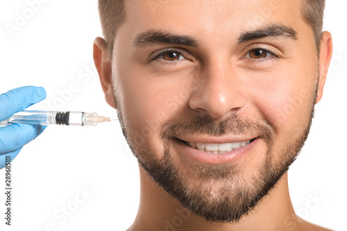 Handsome man receiving filler injection on white background