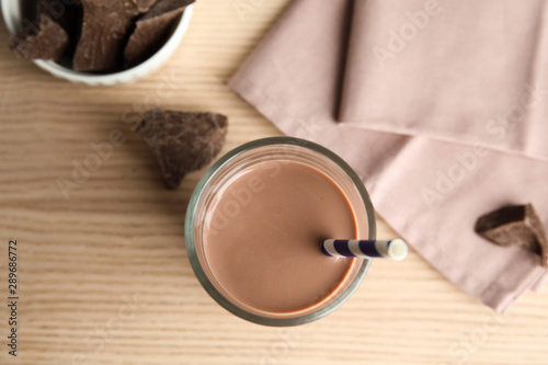 Flat lay composition with glass of tasty chocolate milk on wooden background. Dairy drink