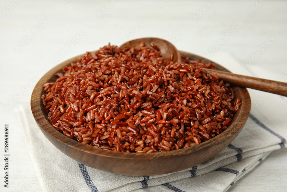 Wooden bowl with delicious cooked brown rice on white table Wooden bowl with delicious cooked brown rice on white table
