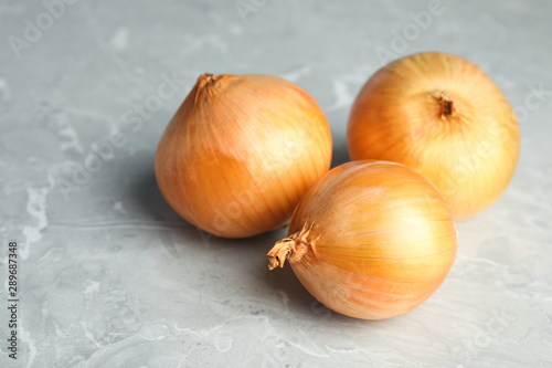 Ripe onions on grey table  space for text