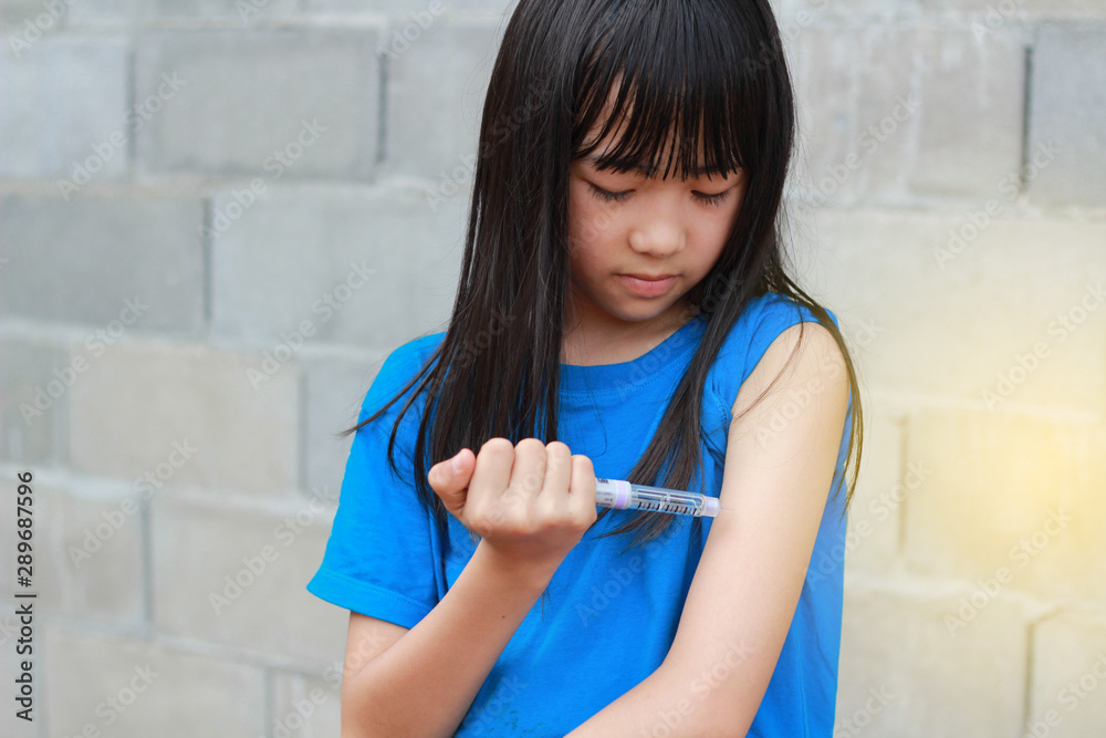 An Asian girl using insulin pen.Self insulin injection.Diabetes in children. An Asian girl using insulin pen.Self insulin injection.Diabetes in children.
