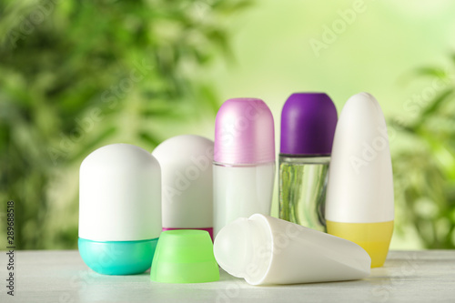 Different deodorants on white wooden table against blurred background