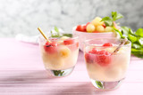Glasses of melon and watermelon ball cocktail on pink wooden table. Space for text