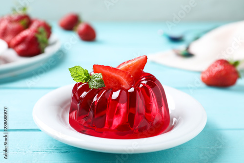 Delicious red jelly with strawberry and mint on light blue wooden table photo