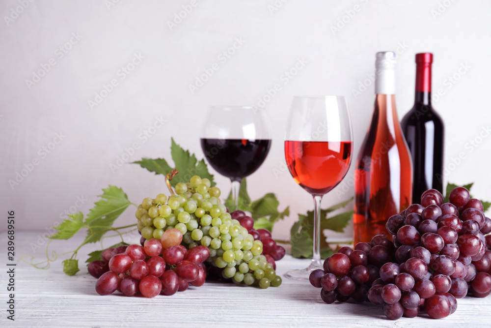 Fresh ripe juicy grapes and wine on white wooden table