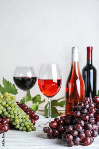 Fresh ripe juicy grapes and wine on white wooden table