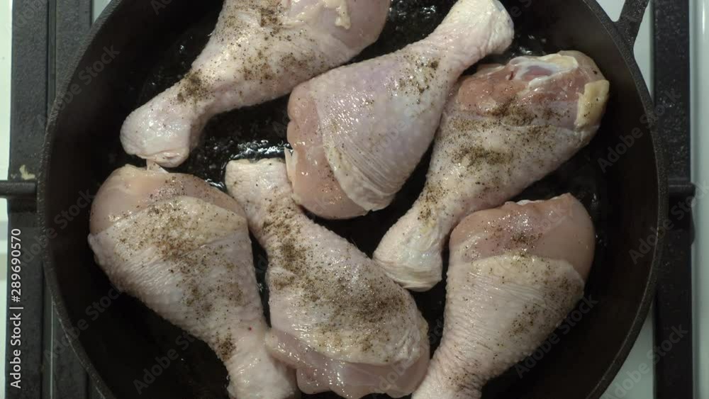 Making pan fried chicken drumsticks in cast iron frying skillet with oil on gas stove top view. Making pan fried chicken drumsticks in cast iron frying skillet with oil on gas stove top view.