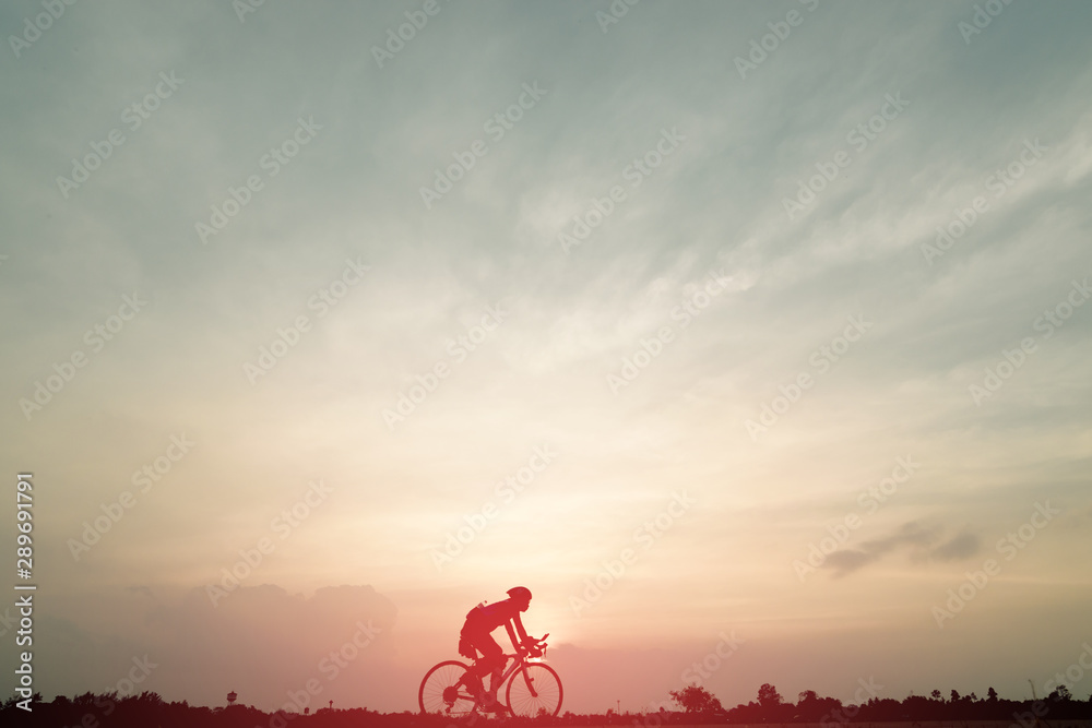 Obraz premium Silhouette of cyclist ride bicycle on sunset background. A man Ride on bike on the road with beautiful colorful sky. Sport and active life concept.