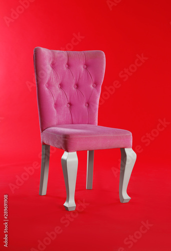 Stylish pink chair on red background. Element of interior design