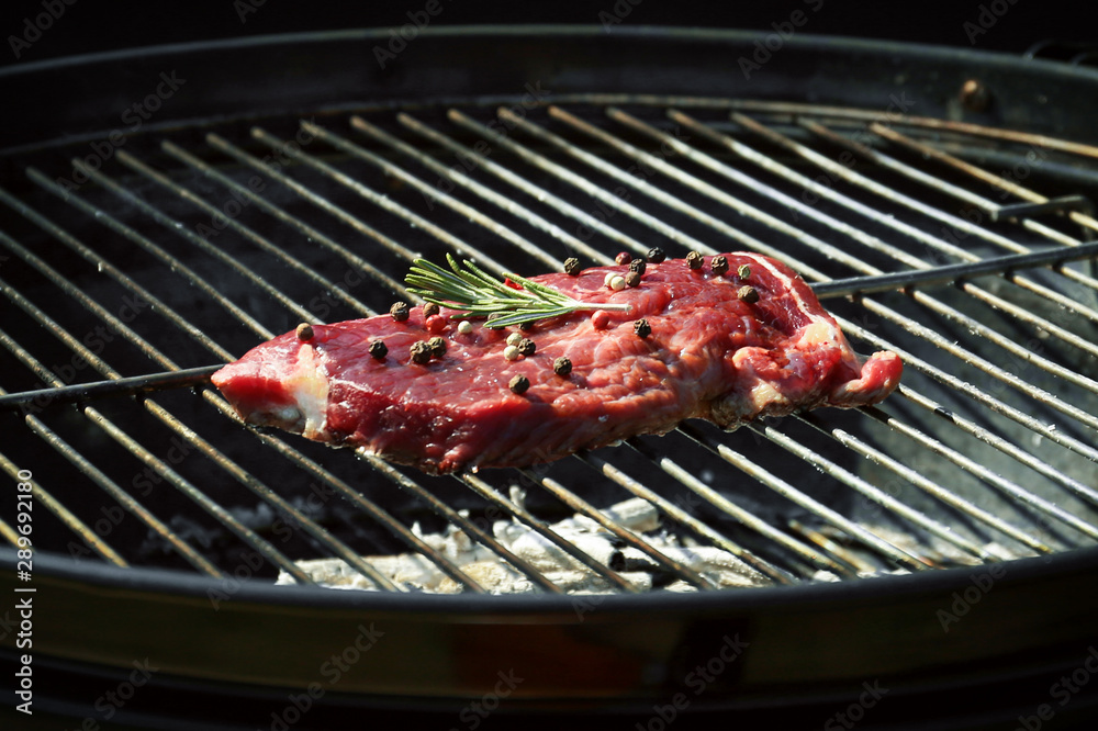 Tasty steak with pepper and rosemary on barbecue grill Tasty steak with pepper and rosemary on barbecue grill