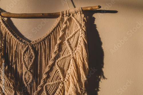 Detailed shot of the macrame wall hanging. DIY boho wall tapestry hanging on the wall in the morning sun