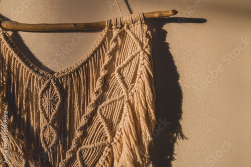 Detailed shot of the macrame wall hanging. DIY boho wall tapestry hanging on the wall in the morning sun photo