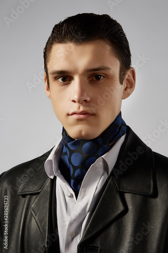 Canvas Print Cropped front view shot of a dark-haired man, wearing white shirt, black jacket and black leather coat