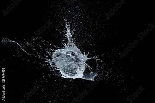 High-speed shot of a water balloon bursting on black background.