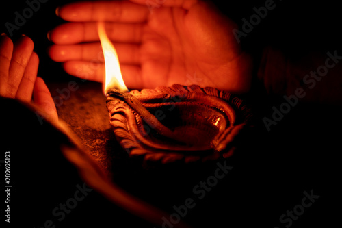 Diwali - A Festival Of Lights. Hand holding or protecting diya or oil lamp, lantern during Diwali celebration. Background picture for Indian Hindu festival Diwali.