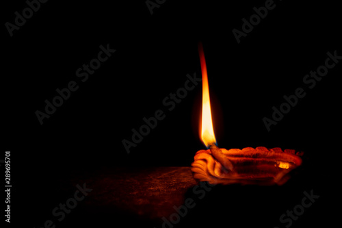 Lit Traditional Clay Diya. Traditional clay diya or oil lamp lit during Diwali celebration as well as kali puja isolated on black background with space for text.