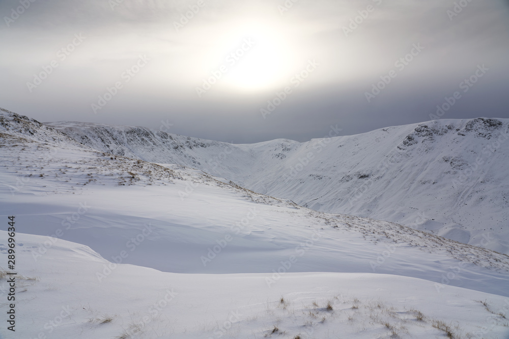 The snow covered summits of High Street and Thornthwaite Crag from Rampsgill Head near Hartsop in the Lake District.