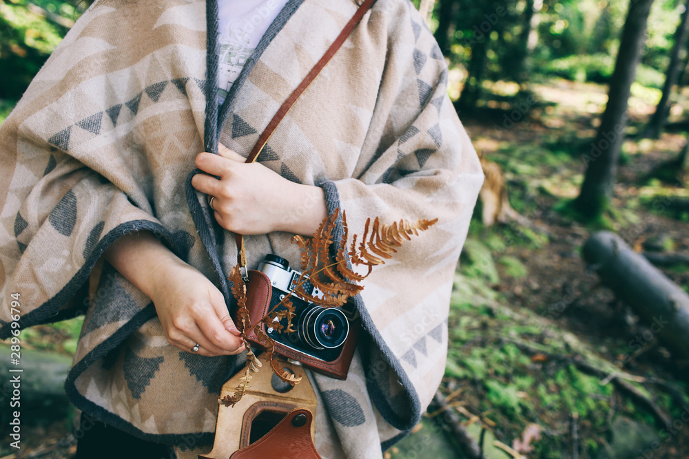 Young girl in a hat and with a vintage camera in the autumn forest