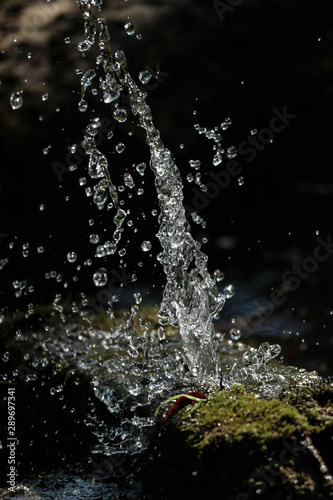 water splashing from an old pipe covered by moss