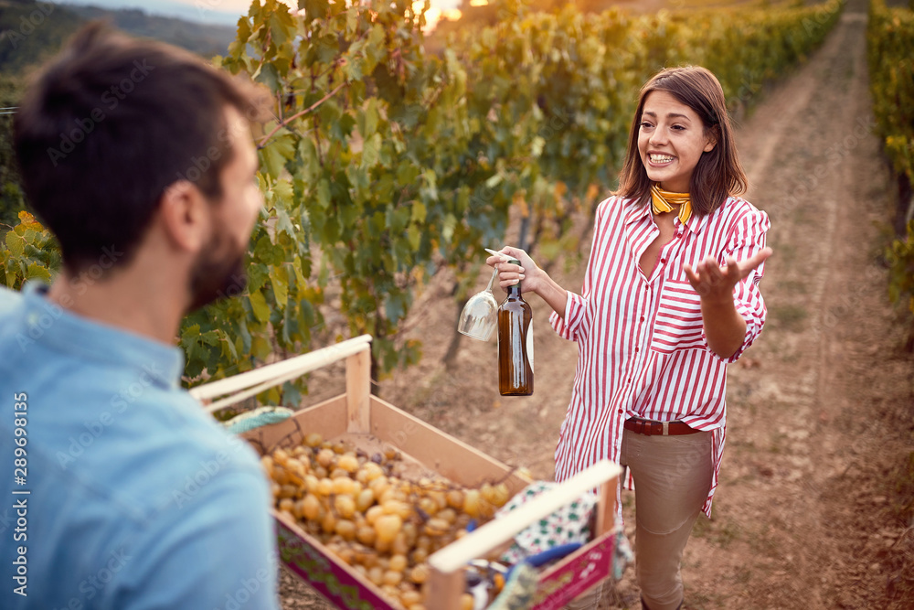 Fototapeta premium Man and woman on autumn vineyard tasting wine.