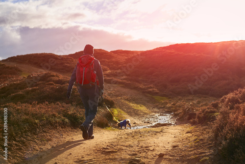 A hiker and their dog walking along a dirt track across Edmundbyers moor and sunset. photo