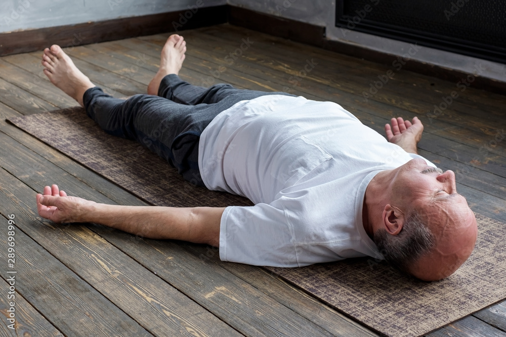 Ταπετσαρία Mature hispanic man in yoga corpse pose in wooden floor