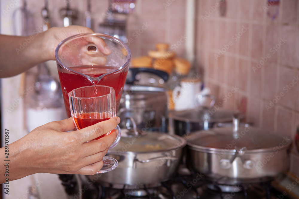 homemade cold sugared strawberry juice in the kitchen filling up the glass