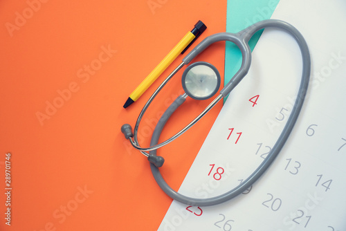 Fotografie Top view of stethoscope and calendar on the color background, schedule to check