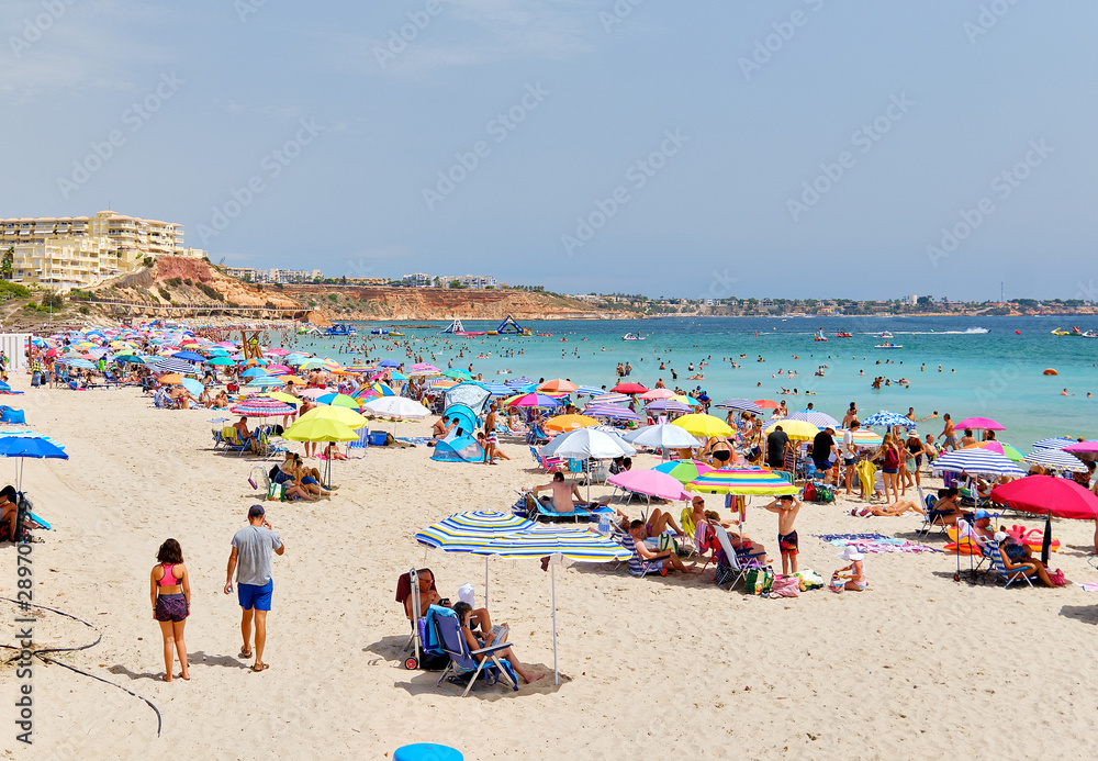 People enjoy summer holidays on the sandy beach Campoamor, Province Alicante, Spain People enjoy summer holidays on the sandy beach Campoamor, Province Alicante, Spain