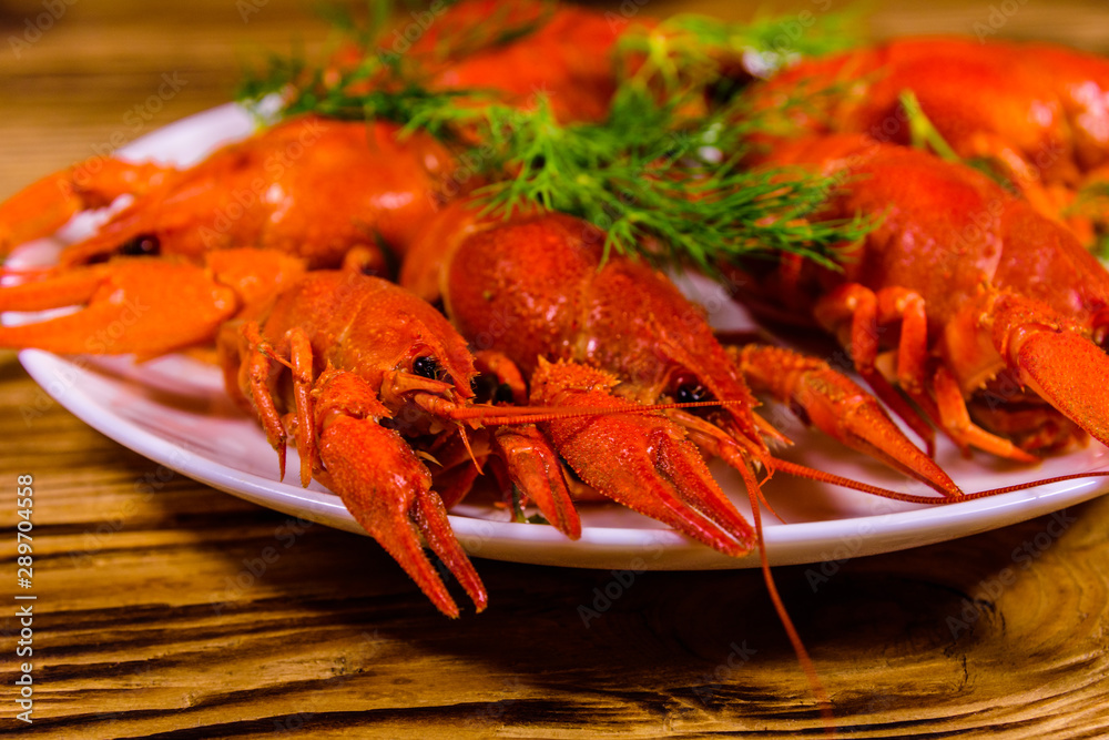 Plate with boiled crayfishes on wooden table Plate with boiled crayfishes on wooden table