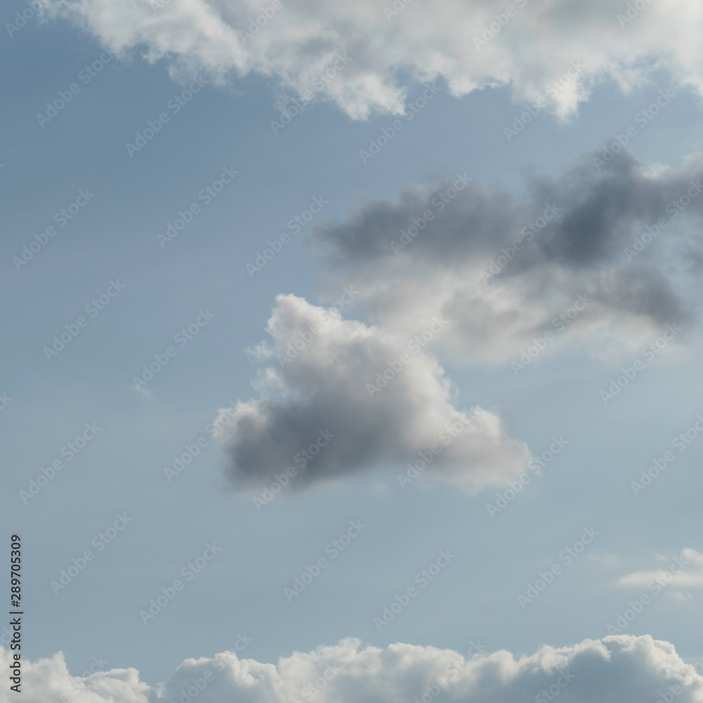 One floating cloud surrounded by other clouds with copy space in the blue air. One floating cloud surrounded by other clouds with copy space in the blue air.