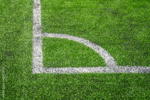 Marking white paint of a corner on a green lawn of the football field.