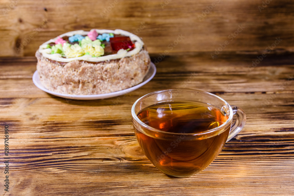 Cup of tea and Kiev cake with cream, nuts and meringue on a wooden table Cup of tea and Kiev cake with cream, nuts and meringue on a wooden table