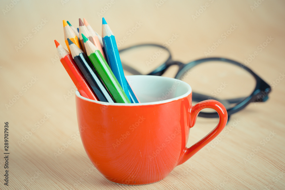 Color pencil in coffee cup on reading table Color pencil in coffee cup on reading table