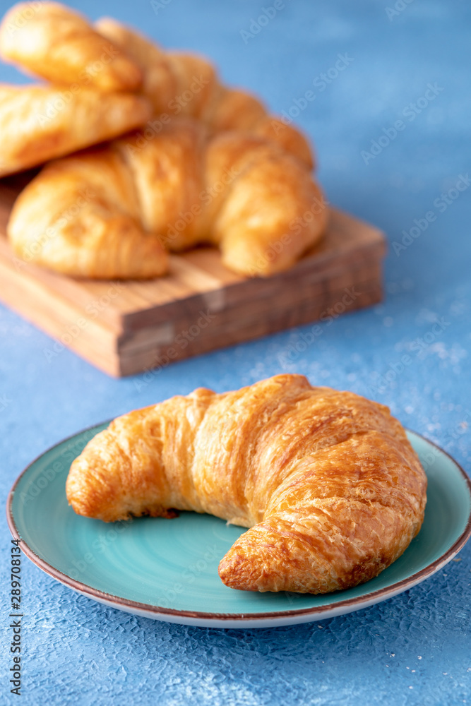 Flacky crispy fresh croissant rolls with blue background