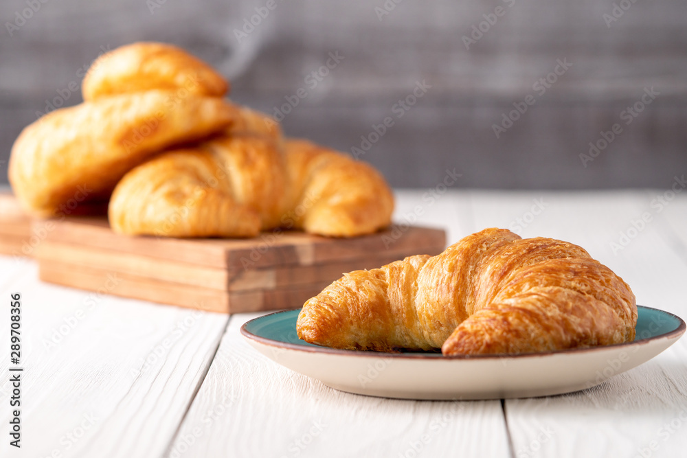 Flacky crispy fresh croissant rolls with blue background