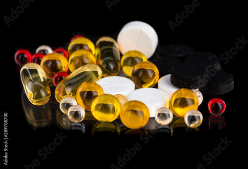 transparent white, yellow and red round medicine capsules and pills on a black and white background