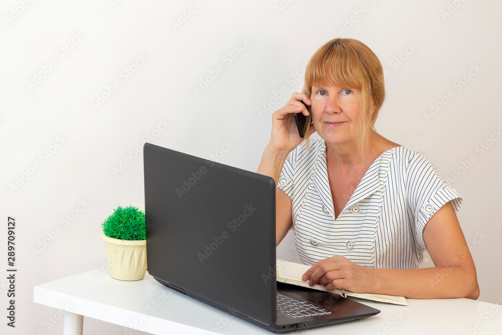 senior woman using laptop. businesswoman working on a laptop at office. businesswoman calling on mobile phone and taking senior woman using laptop. businesswoman working on a laptop at office. businesswoman calling on mobile phone and taking