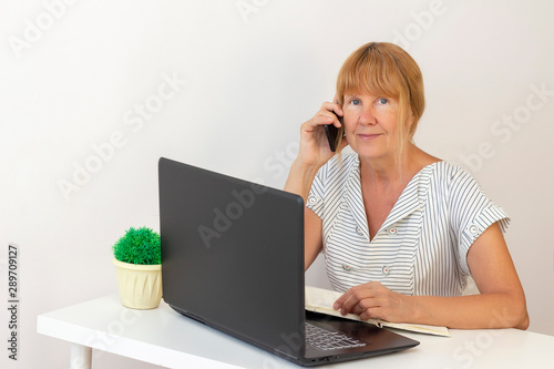 senior woman using laptop. businesswoman working on a laptop at office. businesswoman calling on mobile phone and taking