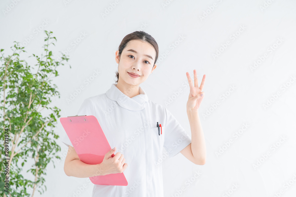 指で「3」をつくる白衣の女性