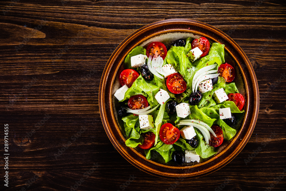 Greek salad in bowl on wooden table