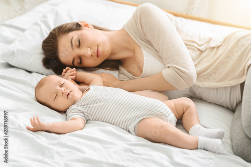 Tired mother sleeping with her newborn son, exhausted after babycare