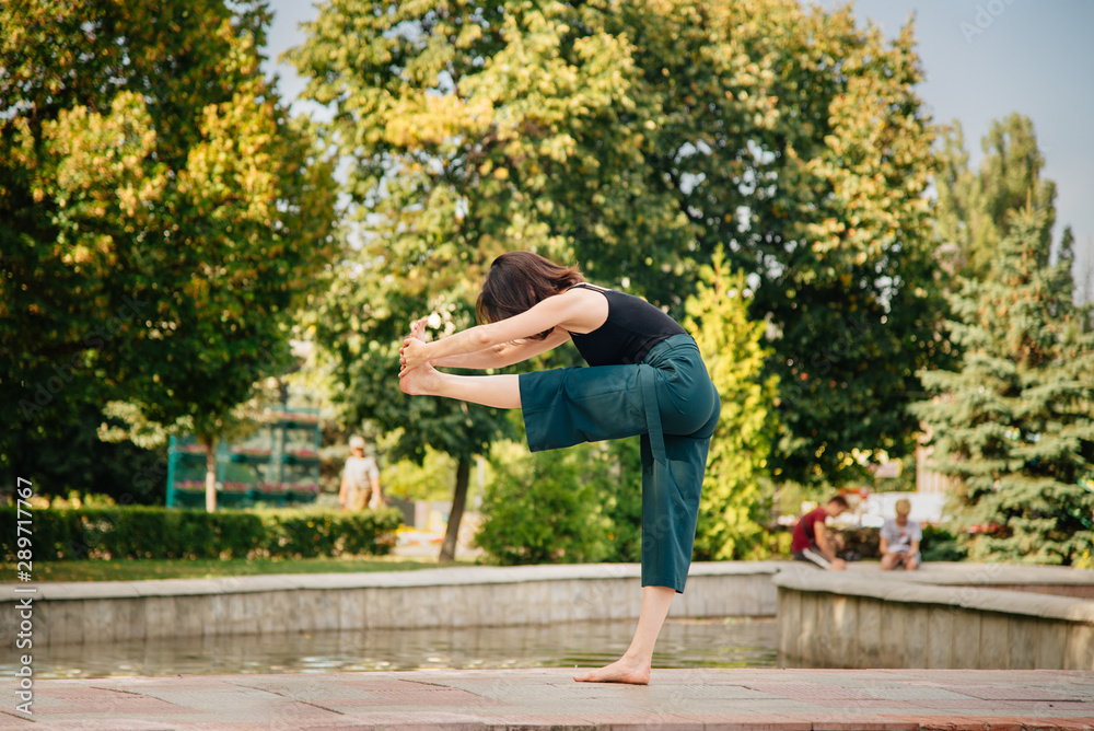 Fototapeta premium young girl in the park is doing yoga asana