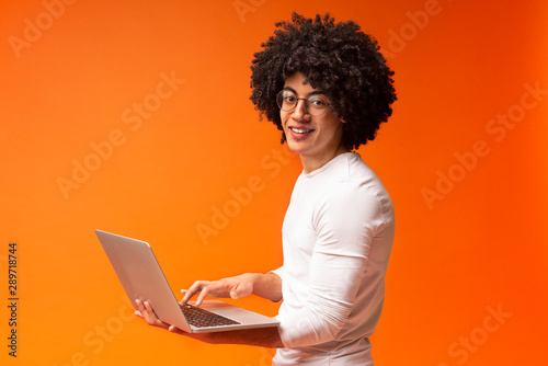 Millennial african guy working on laptop online, using internet