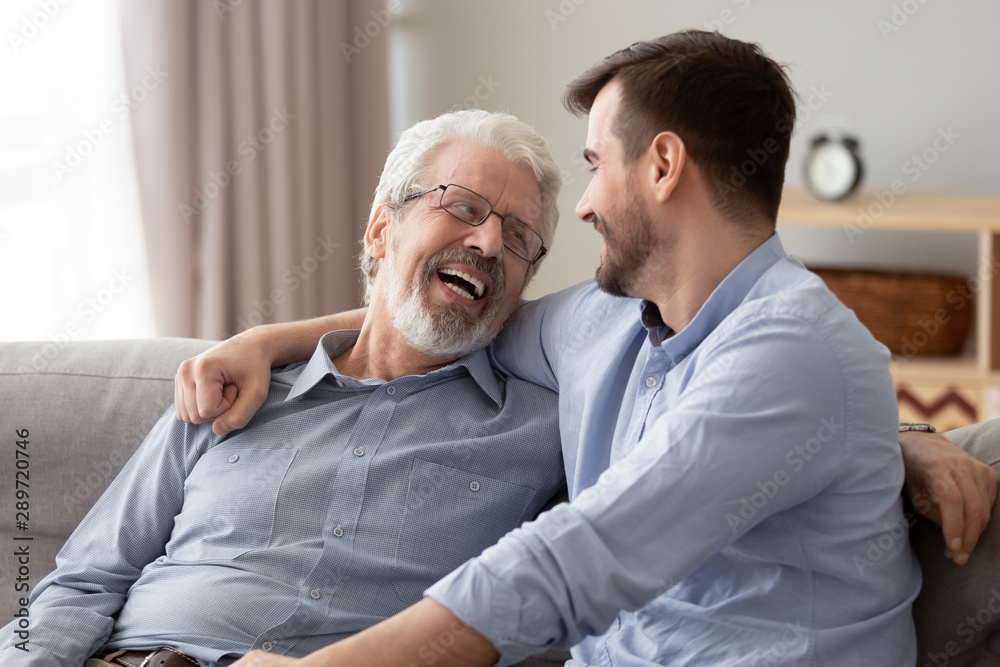 Obraz premium Happy two generations male family laugh talking bonding on sofa