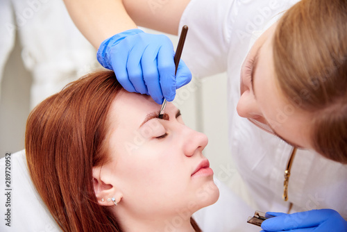 Young woman on eyebrow correction in cosmetology clinic.