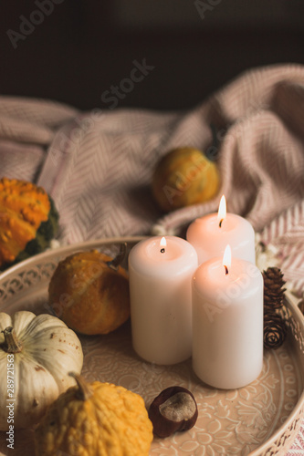 autumn cosy pumpkin, candles and autumn plants on window with led lights bokeh